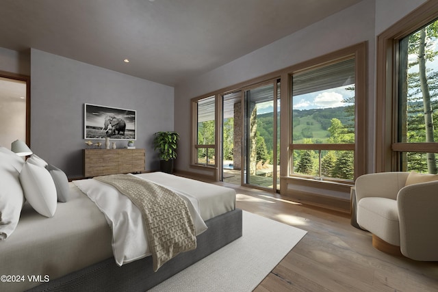 bedroom featuring access to exterior, light wood-type flooring, and multiple windows