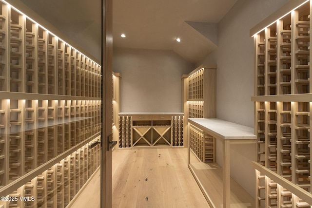 wine cellar featuring light wood-style floors, recessed lighting, and vaulted ceiling