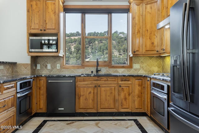 416 Eby Creek Rd, Eagle, CO 81631 - kitchen with stainless steel appliances, inlaid floor details, dark stone countertops, and brown cabinets