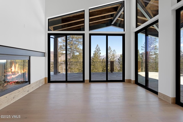 181 Black Bear Trl, Edwards, CO 81632 - unfurnished living room featuring wood finished floors, beamed ceiling, baseboards, and high vaulted ceiling