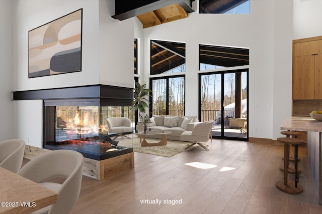 181 Black Bear Trl, Edwards, CO 81632 - living room with baseboards, a multi sided fireplace, beamed ceiling, high vaulted ceiling, and wood finished floors