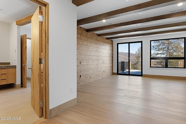 181 Black Bear Trl, Edwards, CO 81632 - spare room featuring visible vents, baseboards, wooden walls, beamed ceiling, and light wood-style flooring