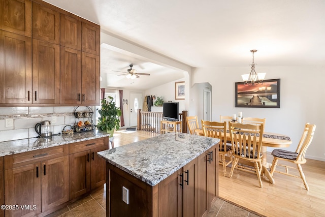 150 River View Rd, Gypsum, CO 81637 - kitchen with ceiling fan, tasteful backsplash, decorative light fixtures, light stone counters, and vaulted ceiling with beams