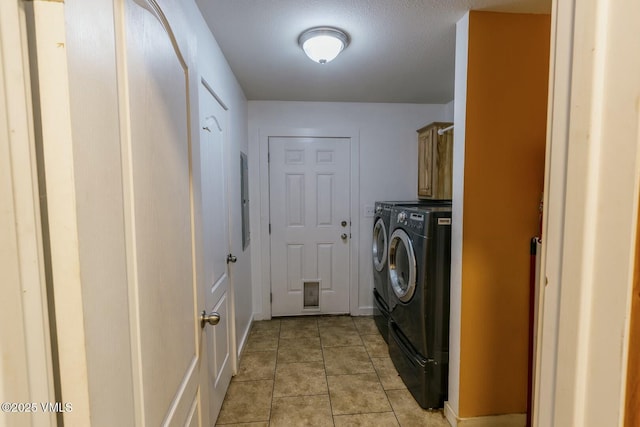 clothes washing area featuring cabinet space, washing machine and dryer, baseboards, and light tile patterned flooring