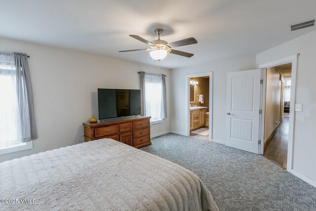 carpeted bedroom featuring visible vents, baseboards, ceiling fan, and ensuite bathroom