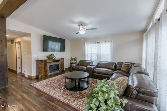 living area with dark wood-style floors, baseboards, visible vents, ceiling fan, and vaulted ceiling