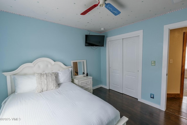 bedroom with a closet, ceiling fan, dark wood-type flooring, and baseboards