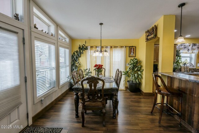 dining area with dark wood finished floors, an inviting chandelier, and baseboards