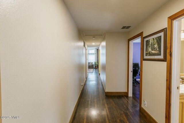 corridor featuring visible vents, baseboards, and dark wood-style flooring