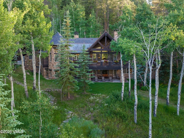140 Elk Woods Rd, Edwards, CO 81632 - back of house featuring a patio area, a chimney, a deck, a wooded view, and a yard