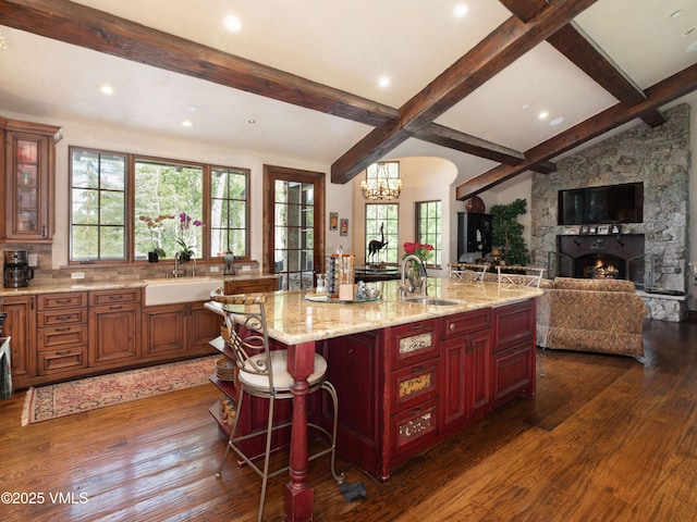 140 Elk Woods Rd, Edwards, CO 81632 - kitchen featuring beam ceiling, dark wood finished floors, light stone counters, a breakfast bar, and a stone fireplace