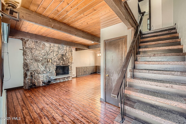 stairs with a fireplace, wood ceiling, beamed ceiling, and wood finished floors