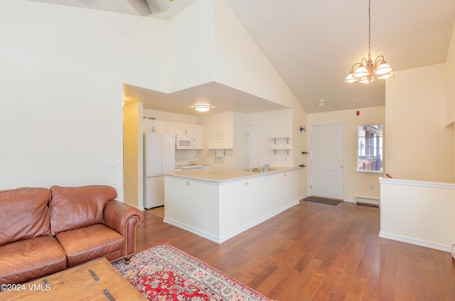 kitchen featuring open floor plan, light countertops, baseboard heating, white cabinets, and white appliances