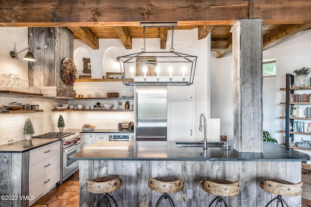 767 Charolais Cir, Edwards, CO 81632 - kitchen featuring high end appliances, open shelves, tasteful backsplash, a breakfast bar area, and dark tile patterned floors