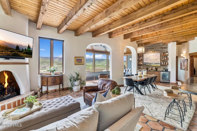 767 Charolais Cir, Edwards, CO 81632 - living room featuring beverage cooler, a wood ceiling with exposed beams, arched walkways, and a lit fireplace