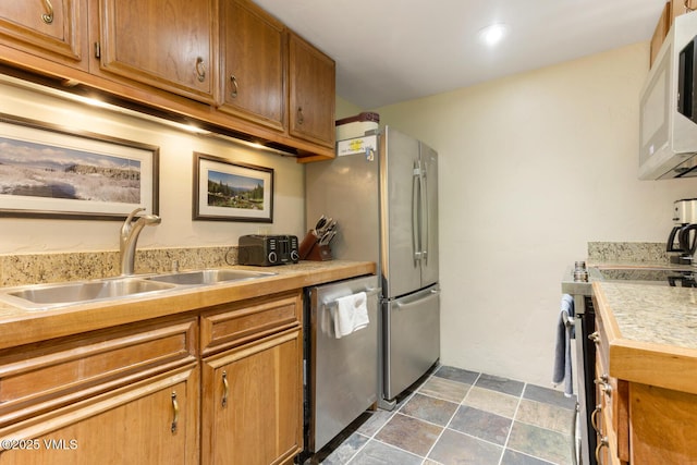 2821 Basingdale Blvd Unit 4, Vail, CO 81657 - kitchen with stainless steel appliances, a sink, brown cabinets, light countertops, and dark stone finish floors