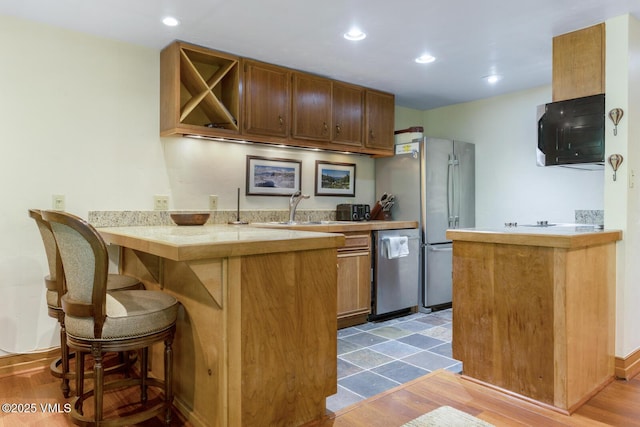 2821 Basingdale Blvd Unit 4, Vail, CO 81657 - kitchen with a peninsula, stainless steel appliances, light countertops, a breakfast bar, and wood finished floors