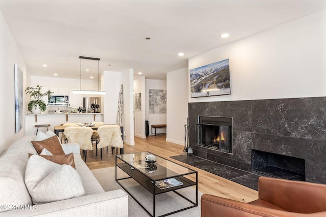 living area with recessed lighting, light wood finished floors, and a tiled fireplace