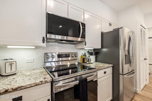 kitchen with appliances with stainless steel finishes, light wood finished floors, decorative backsplash, and light stone countertops