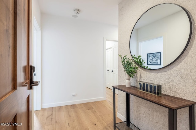 hall with light wood-type flooring and baseboards