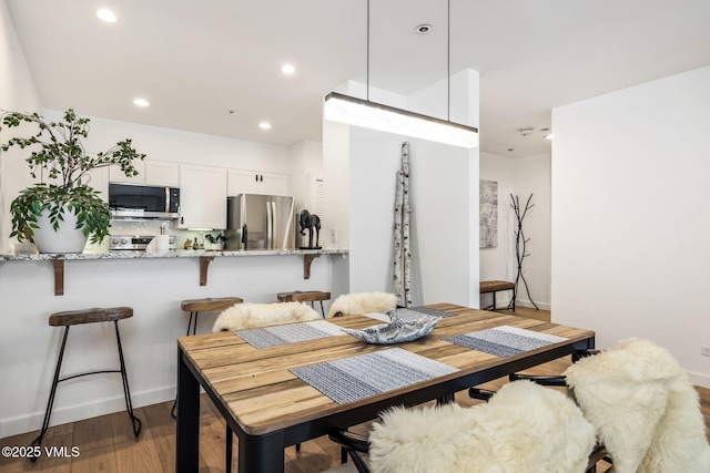 dining room with baseboards, wood finished floors, and recessed lighting