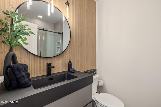 bathroom with toilet, a stall shower, and vanity