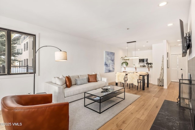 living area featuring recessed lighting, baseboards, and light wood finished floors