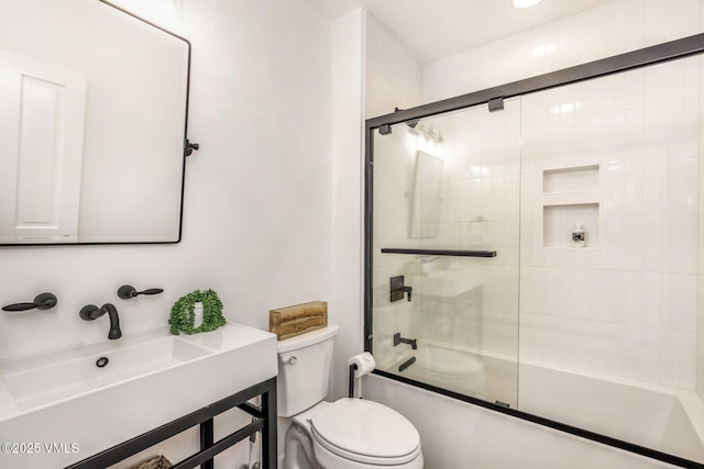 bathroom featuring combined bath / shower with glass door, a sink, and toilet