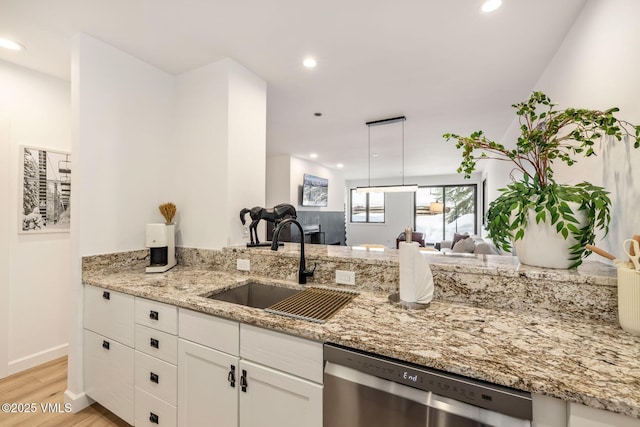 kitchen with light wood finished floors, dishwasher, light stone counters, white cabinetry, and a sink