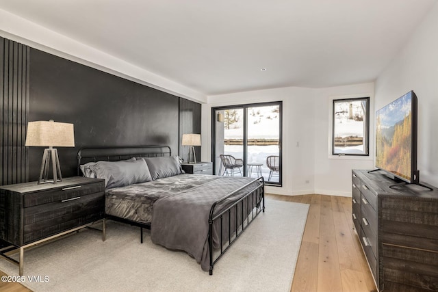 bedroom with access to outside, light wood-type flooring, and baseboards