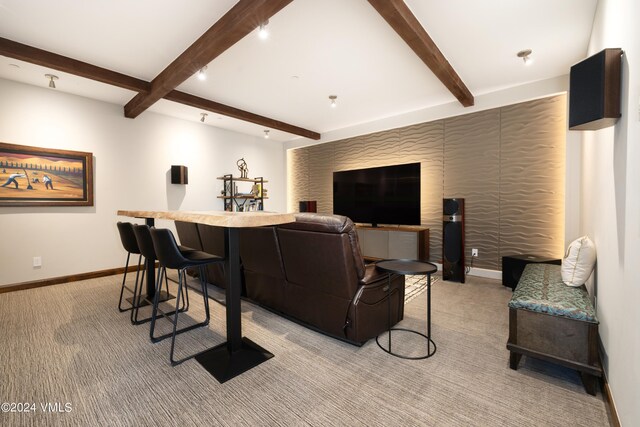 cinema room featuring light carpet, baseboards, and beam ceiling