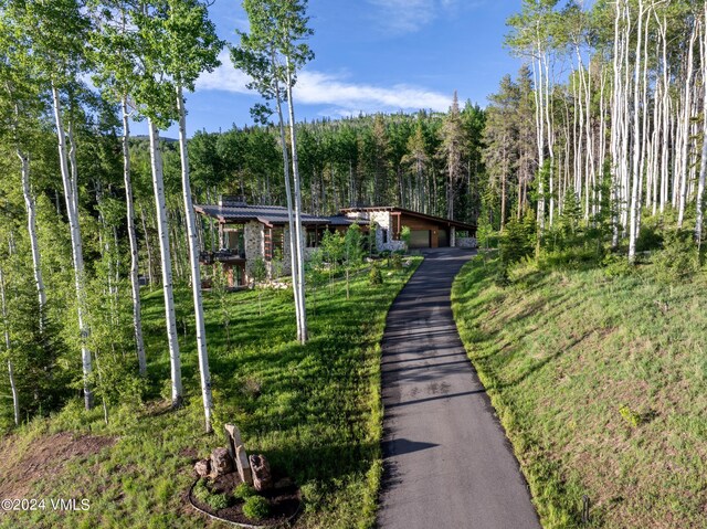 view of front of house with a forest view and a front lawn