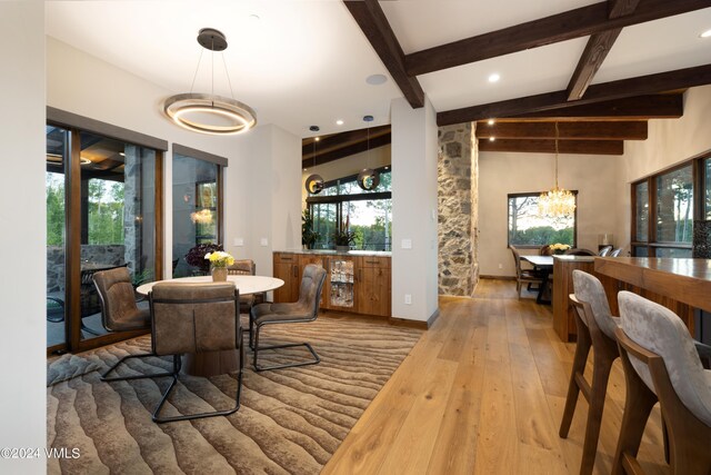 dining space with a healthy amount of sunlight, wood finished floors, and beamed ceiling