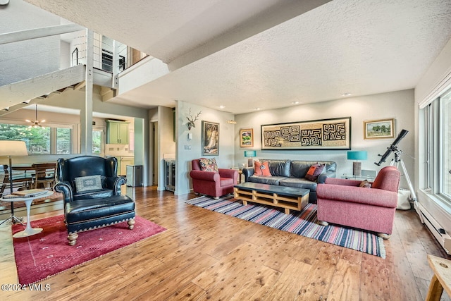 living room featuring hardwood / wood-style flooring, baseboard heating, a textured ceiling, and a notable chandelier