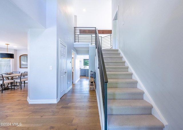 stairs with a high ceiling and wood-type flooring