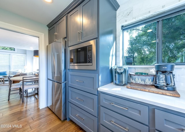 kitchen featuring built in microwave, stainless steel fridge, gray cabinetry, and light hardwood / wood-style floors