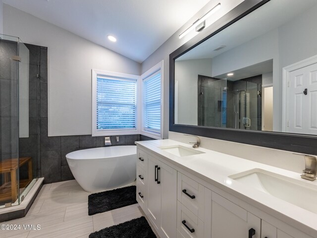 bathroom with vanity, lofted ceiling, tile walls, and separate shower and tub