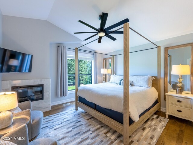 bedroom with lofted ceiling, a high end fireplace, and light hardwood / wood-style flooring