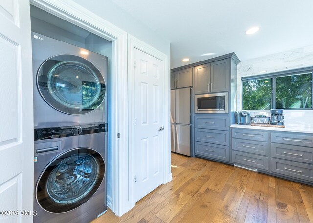 washroom featuring light wood-type flooring and stacked washer / dryer