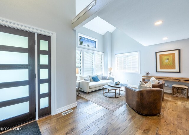 living room featuring wood-type flooring and high vaulted ceiling