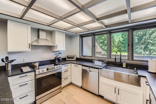 1750 S Frontage Rd W Unit E-3, Vail, CO 81657 - kitchen with wall chimney exhaust hood, appliances with stainless steel finishes, light wood-style floors, coffered ceiling, and beamed ceiling