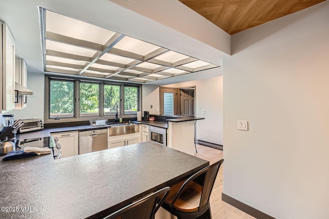 1750 S Frontage Rd W Unit E-3, Vail, CO 81657 - kitchen featuring dishwasher, a peninsula, dark countertops, light wood-type flooring, and coffered ceiling