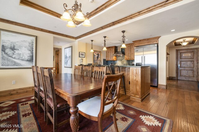 dining room with dark hardwood / wood-style flooring, a tray ceiling, crown molding, and a chandelier