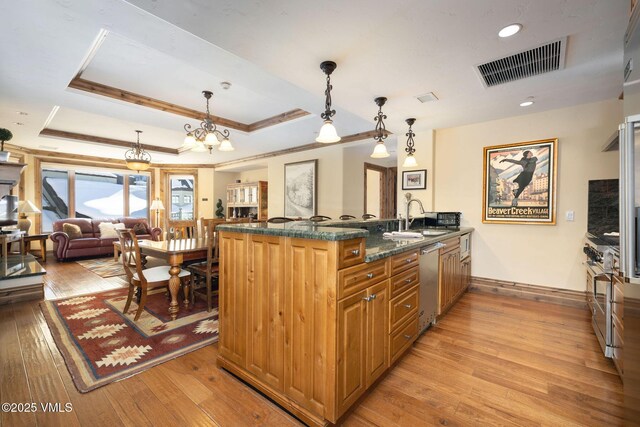 kitchen featuring sink, dishwasher, a tray ceiling, decorative light fixtures, and kitchen peninsula