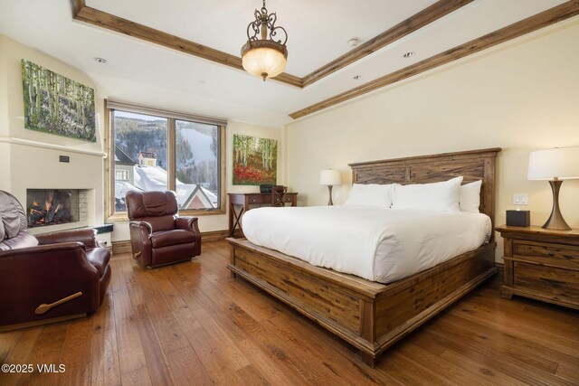 bedroom with crown molding, hardwood / wood-style floors, and a tray ceiling