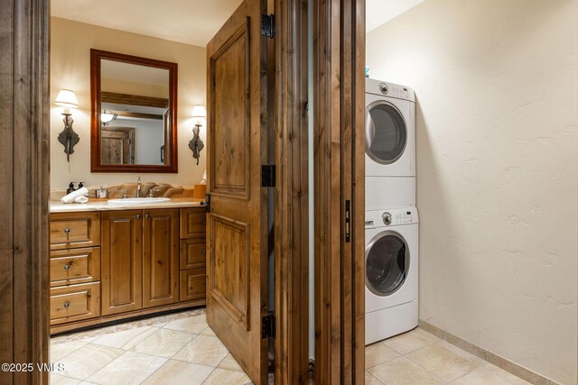 laundry room with stacked washing maching and dryer, sink, and light tile patterned floors