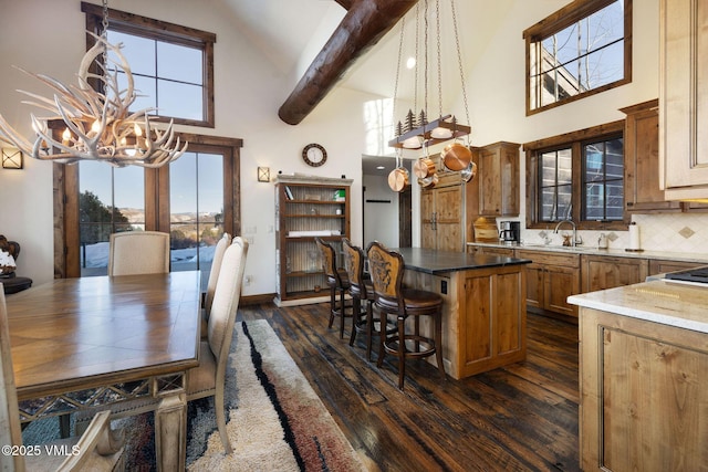 dining room featuring dark wood finished floors, an inviting chandelier, beam ceiling, and high vaulted ceiling