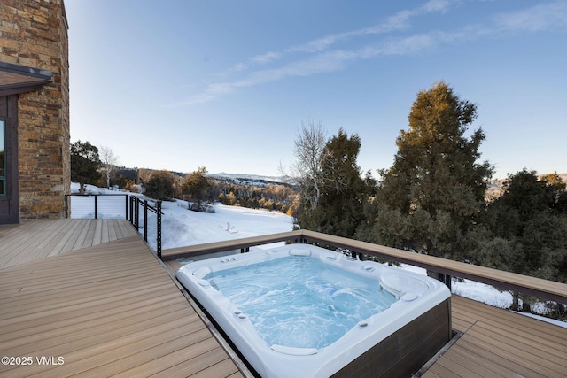 snow covered deck featuring hot tub deck surround