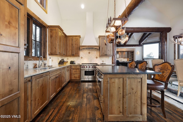 kitchen featuring a breakfast bar area, a sink, custom range hood, designer stove, and a center island