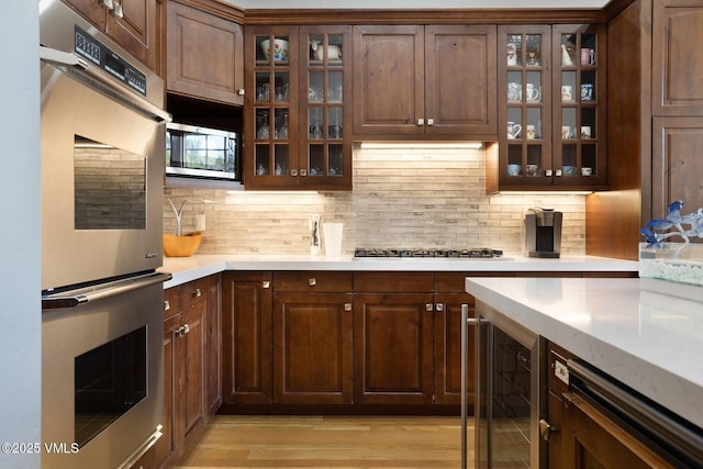 124 Grey Hawk Ln, Edwards, CO 81632 - kitchen featuring stainless steel appliances, light countertops, beverage cooler, decorative backsplash, and light wood-style floors